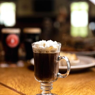 Irish Coffee served in a stemmed glass with a handle, topped with whipped cream.