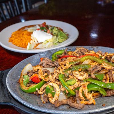 Sizzling chicken and steak fajitas served with Mexican rice, beans, and fresh toppings.