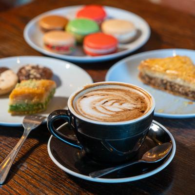 Cup of coffee and assorted desserts served on a wooden table.