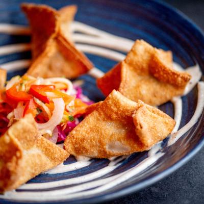 Golden-brown fried dumplings arranged around a colorful vegetable garnish of peppers and cabbage.
