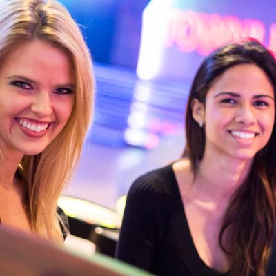 Two people smiling brightly next to each other indoors.
