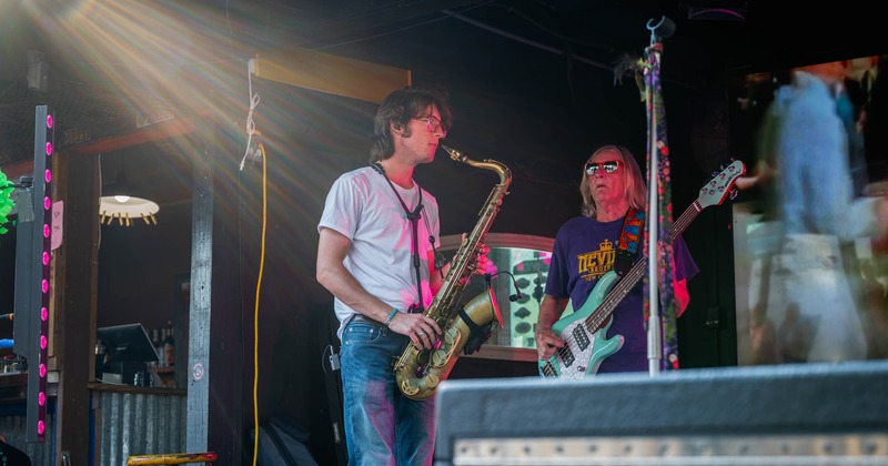 Musicians play saxophone and bass guitar on stage