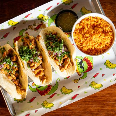 Chipotle chicken tacos with a side of rice and dipping sauce.