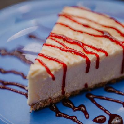 Cheesecake slice drizzled with strawberry sauce.