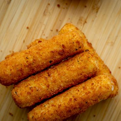 Breaded mozzarella sticks served on a wooden board.