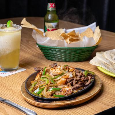 Fajita on hot skillet choice of meat grilled green onion and pepper.