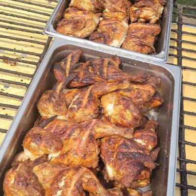 Several large trays of barbecue chicken pieces.