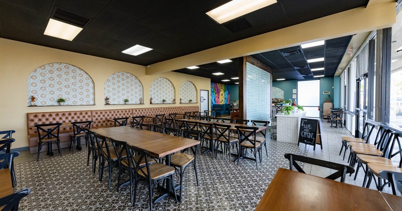 Interior, long table setups with chairs, restaurant entrance and shop window on the right