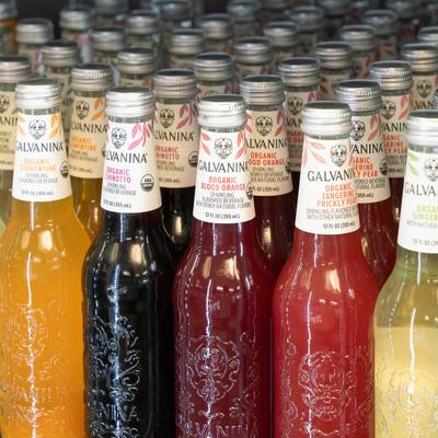 Rows of colorful bottles of organic sparkling beverages, with assorted flavors.
