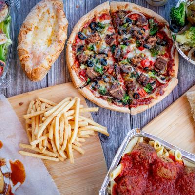 Overhead view of assorted dishes such as meatballs, pizza, chicken parmesan sub, fries.