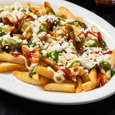 French fries topped with crema, red salsa, cilantro sauce, and crumbled white cheese.