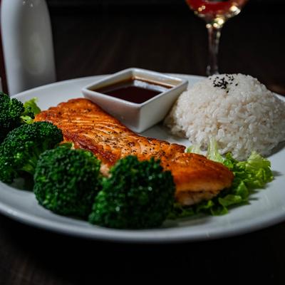 Salmon Teriyaki served on a white plate with steamed broccoli, rice and soy sauce.