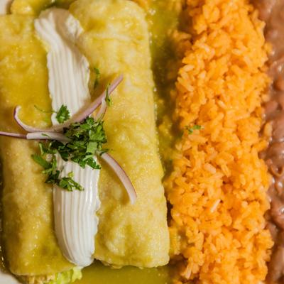 Chicken enchiladas smothered in green sauce, with rice, and beans.