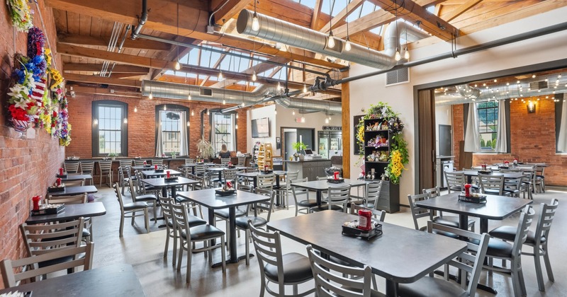 Spacious restaurant with wooden ceiling beams, brick walls, and large windows