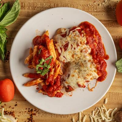 Chicken Parmigiana served with penne pasta with tomato sauce.