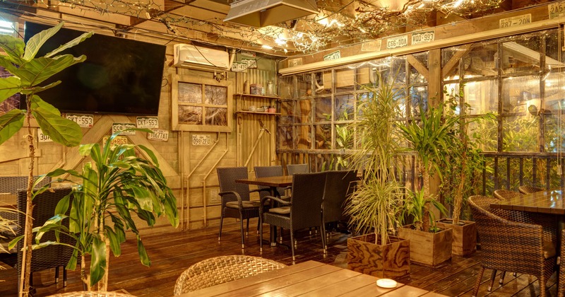 Interior, dining area, tables with chairs, wood coated walls, lavish plant decoration