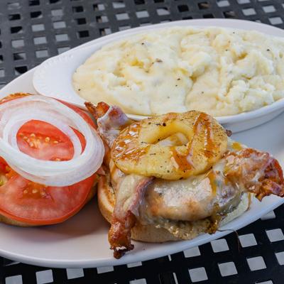 Hawaiian Chicken Sandwich topped with bacon and a pineapple ring, alongside mashed potatoes.