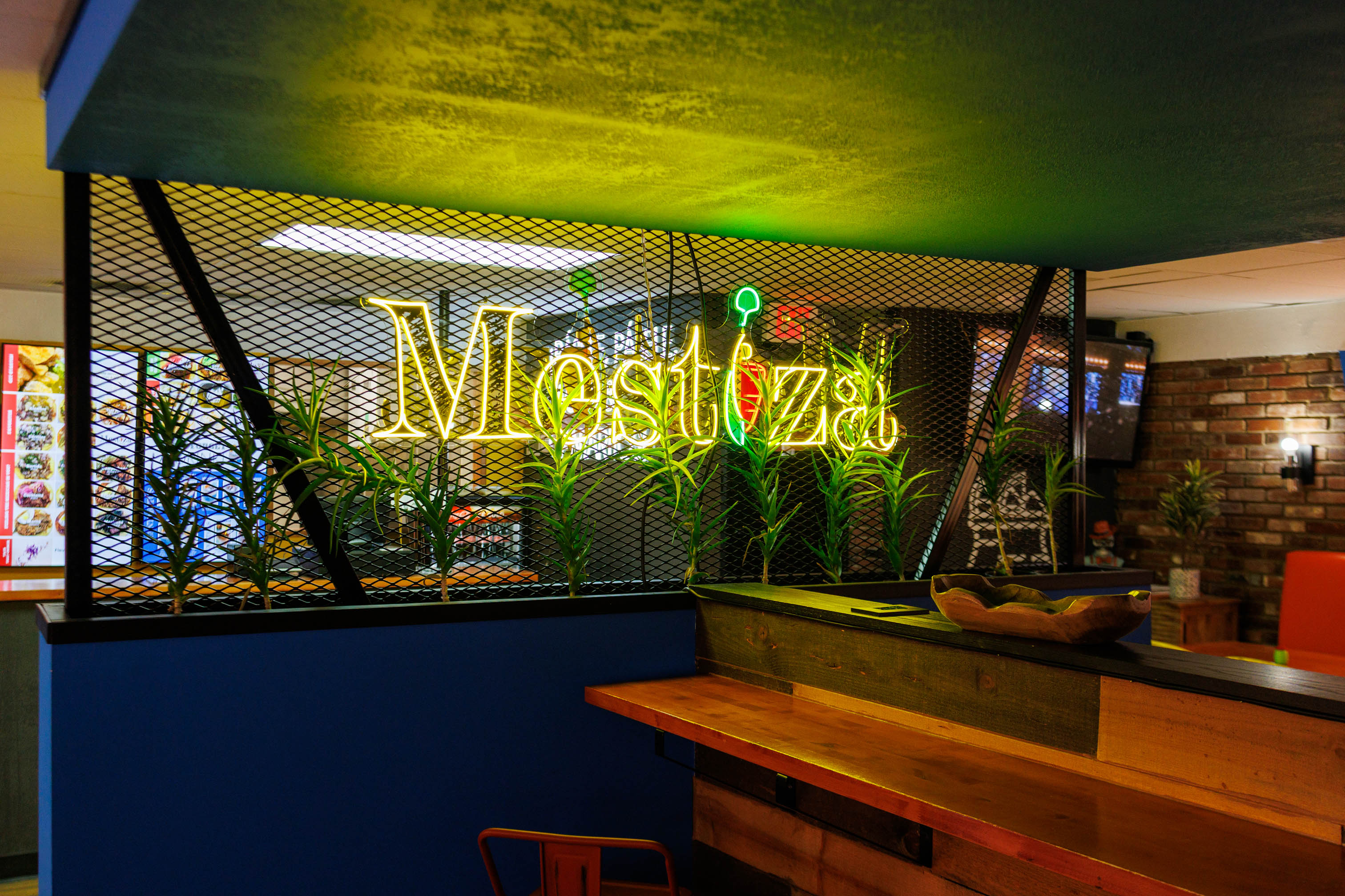 A prominent neon sign with the restaurant name set behind a decorative metal mesh screen