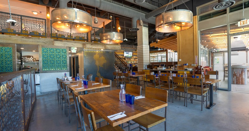 Interior, wooden counter top tables for four, six and eight with chairs, patio exit, concrete floor