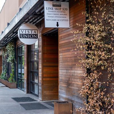 Vista Union exterior, wooden facade adorned with climbing plants and hanging signs.
