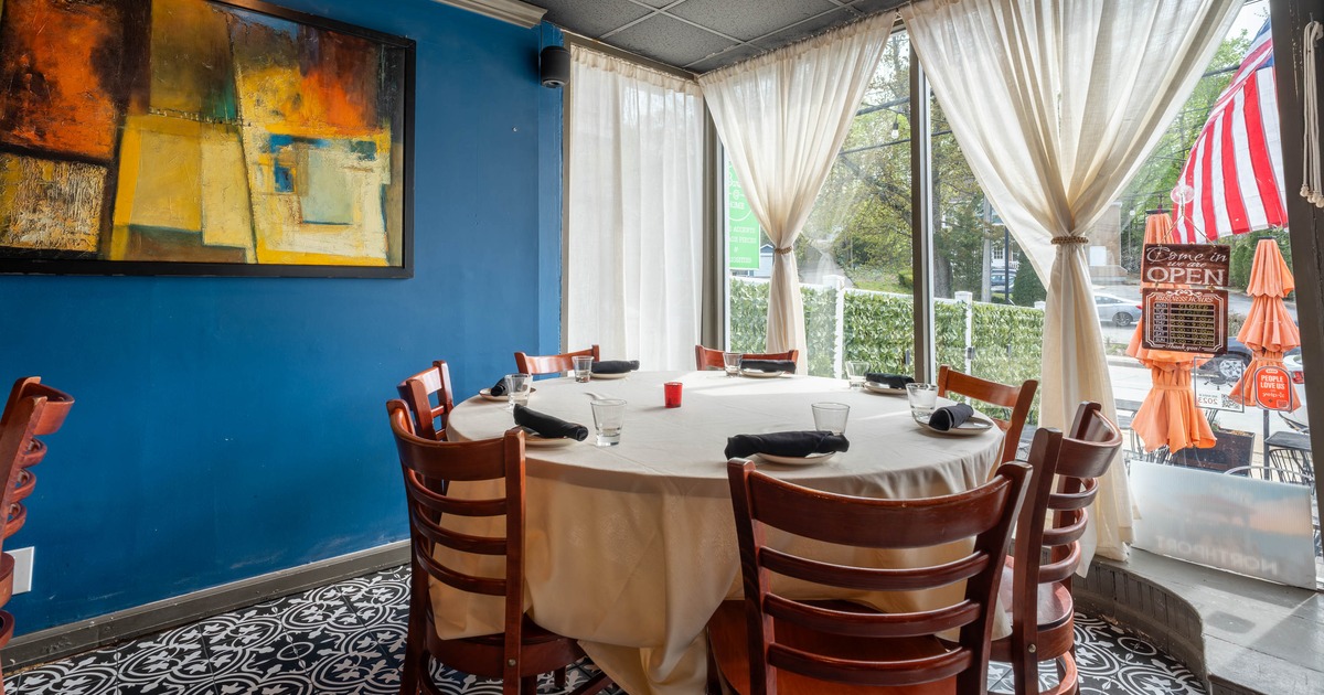 Interior - a round table set for six, a blue wall, abstract painting, large windows, sheer curtains