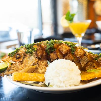 Whole grilled fish accompanied by a mound of white rice and fried plantains.