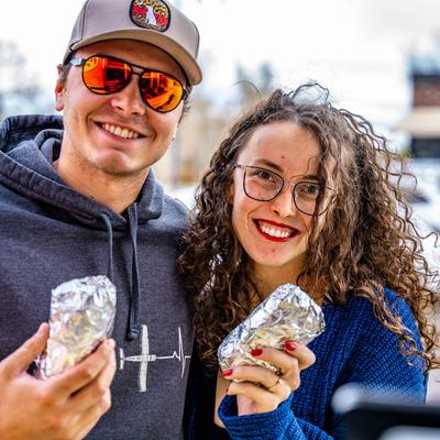 Customers holding burritos.