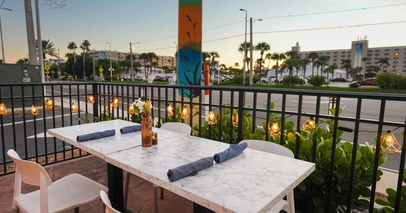 Outdoor dining area - a marble table, white chairs and decorative string lights.