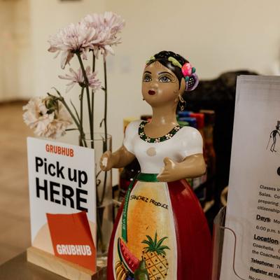 Pickup sign next to a hand-pained Mexican ceramic doll figurine and flowers.