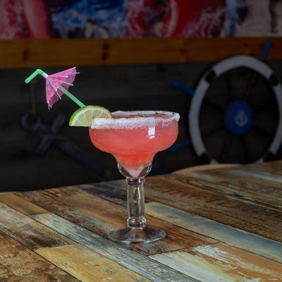 Red margarita with lime wedge and paper umbrella.