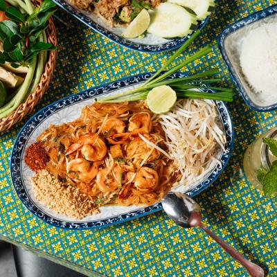 Shrimp Pad Thai on a table with other food, top view.
