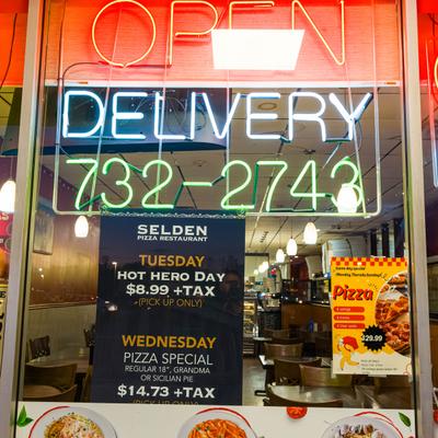 Restaurant window with bright neon delivery sign.