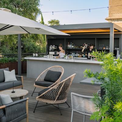 Outdoor bar area with a counter, table seating, string lights and umbrellas.
