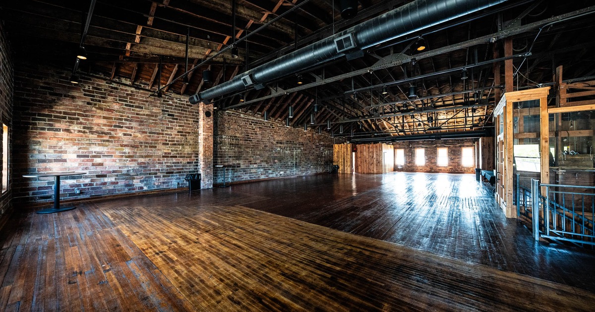 Large hall with exposed brick walls, wooden floors, and high ceilings