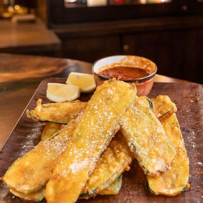Fried zucchini served with marinara sauce and lemon wedges.