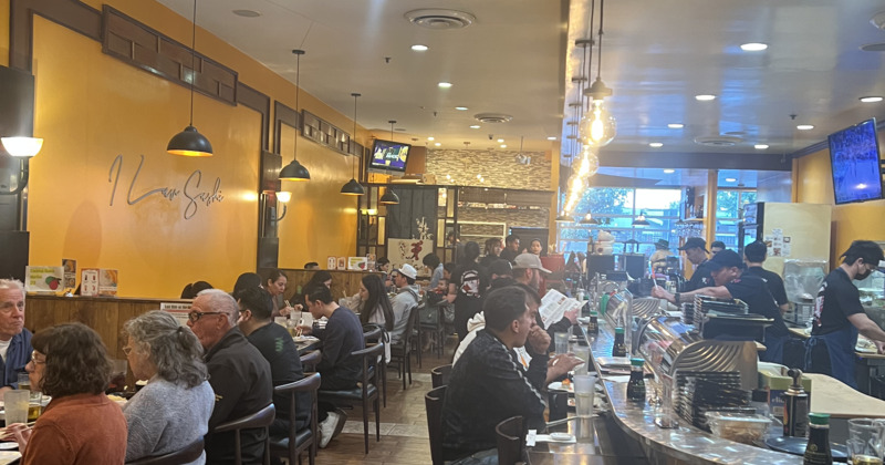 A bustling restaurant filled with diners enjoying meals and drinks at various tables