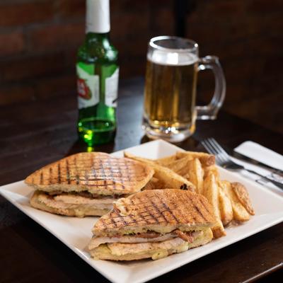 Meat sandwich with a side of fries and beer.