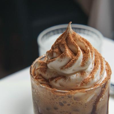 A creamy chocolate beverage topped with a swirl of whipped cream and cocoa.