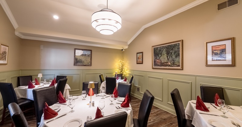 Private dining room with fully set tables and framed wall paintings
