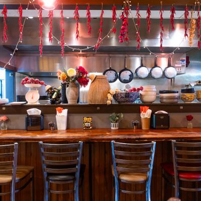 Interior, food counter, chairs in front, kitchen in the back.