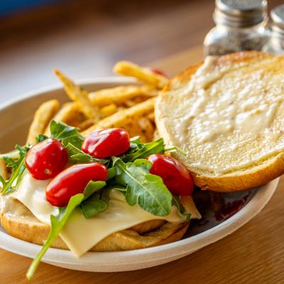 Salmon Burger topped with cheese, arugula and cherry tomatoes, served with fries.