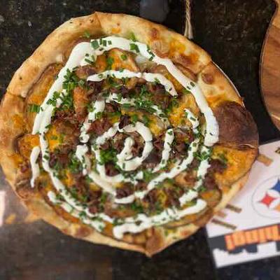 A pizza topped with various ingredients and a creamy white sauce drizzled in a spiral pattern.