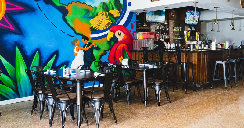 Interior of a restaurant with colorful mural and bar area