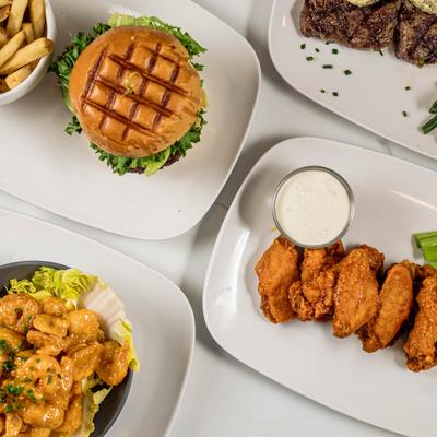 Chicken wings, shrimp, fries, and a burger on a table.