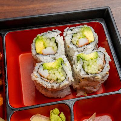 Bento box featuring sushi rolls containing crab meat, avocado, and cucumber, close-up.