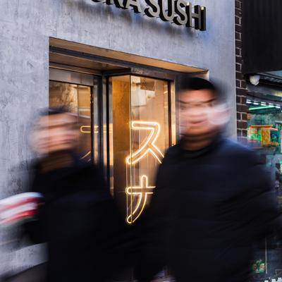 Exterior, people on side walk in front of the restaurant entrance.