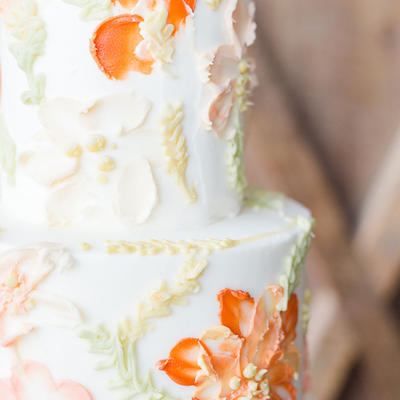 Close-up of a white tiered cake featuring delicate floral icing decorations