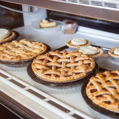 A display case filled with various baked goods, primarily pies.