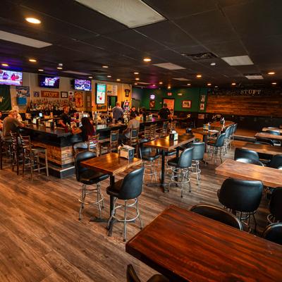 Interior with a bar, wooden tables, and black chairs.