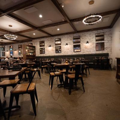 Dining area's interior with tables, chairs and several circular crystal chandeliers.